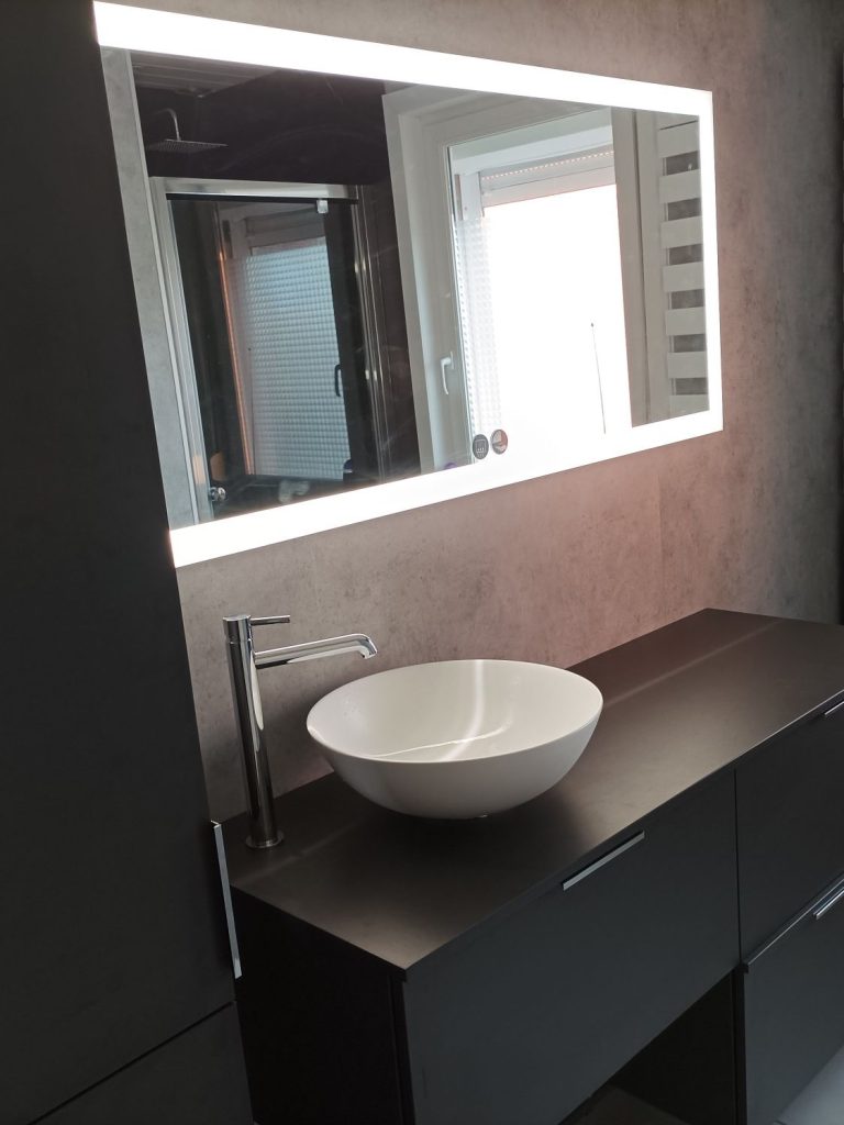 Lavabo moderne : Vasque blanche sur meuble noir avec grand miroir.