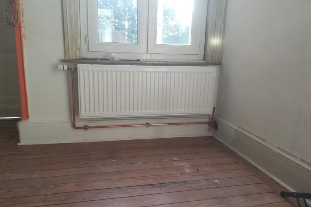 Radiateur classique : Radiateur blanc installé sous une fenêtre.