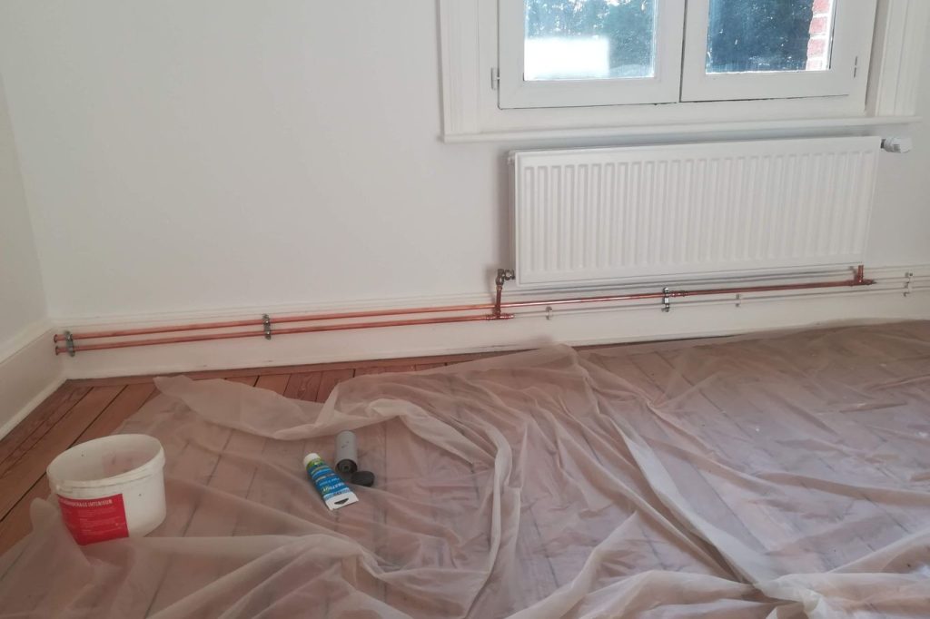 Chantier chauffage : Tuyaux au sol protégés par une bâche en plastique.