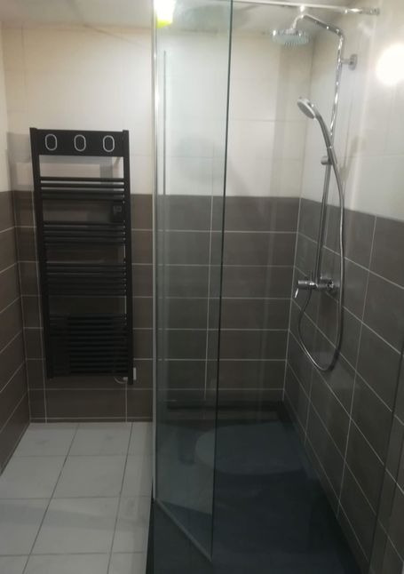 Salle de bain grise : Douche moderne avec porte-serviettes noir.